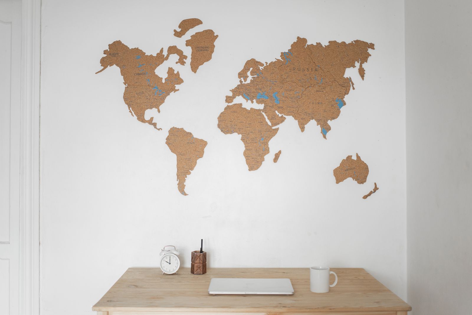 Minimalist workspace with a world map, laptop, and clock